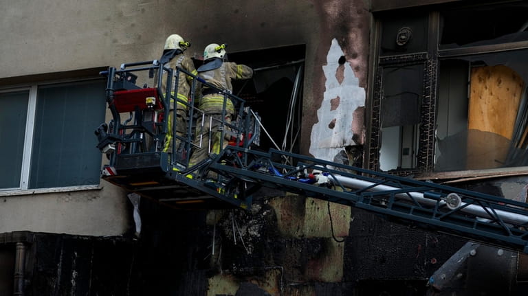 Firefighters work in the aftermath of a fire in a...