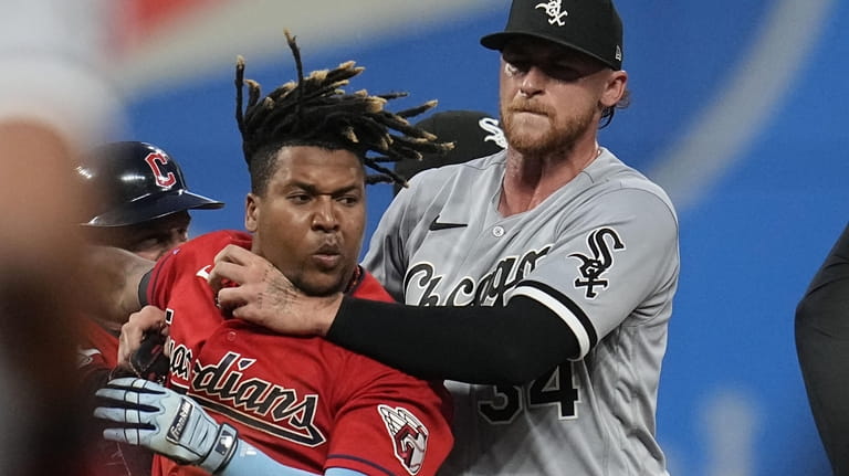Chicago White Sox's Michael Kopech, right, holds back Cleveland Guardians'...