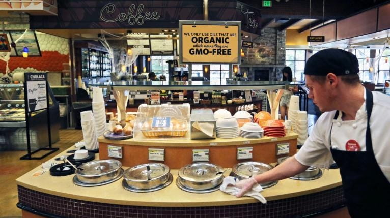 A grocery store employee wipes down a soup bar with...