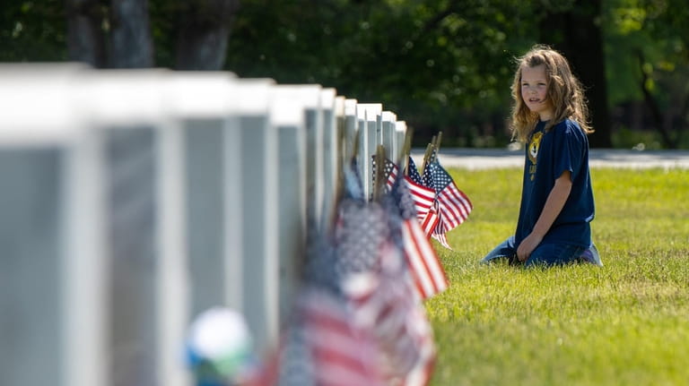 Annie Poppe, 6, of Oakdale sits near her grandfather's headstone at...