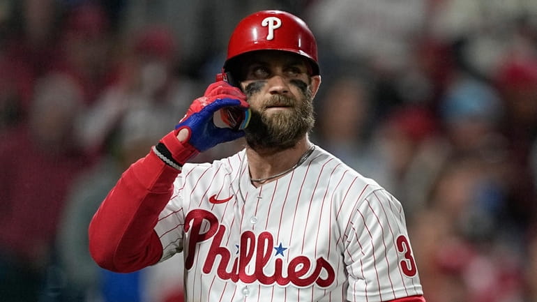 The Phillies' Bryce Harper walks to the dugout after striking...