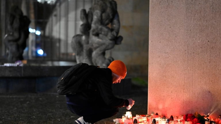 A mourner lays a candle light outside the building of...