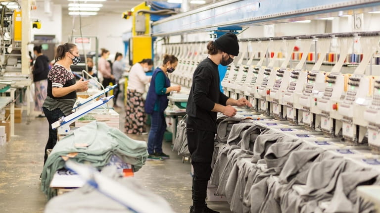 Workers operate machines to embroider sweatshirts at David Peyser Sportswear...