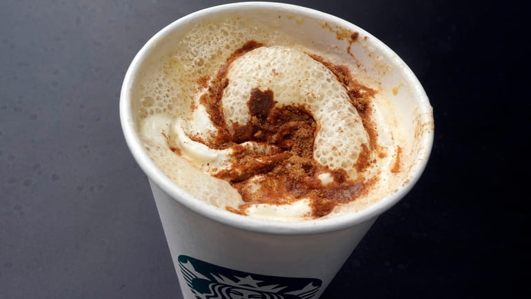 A Pumpkin Spice Latte drink rests on a table at...