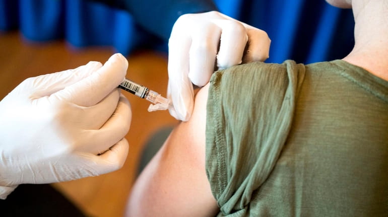 A pharmacist administers a flu shot at Molloy College in...