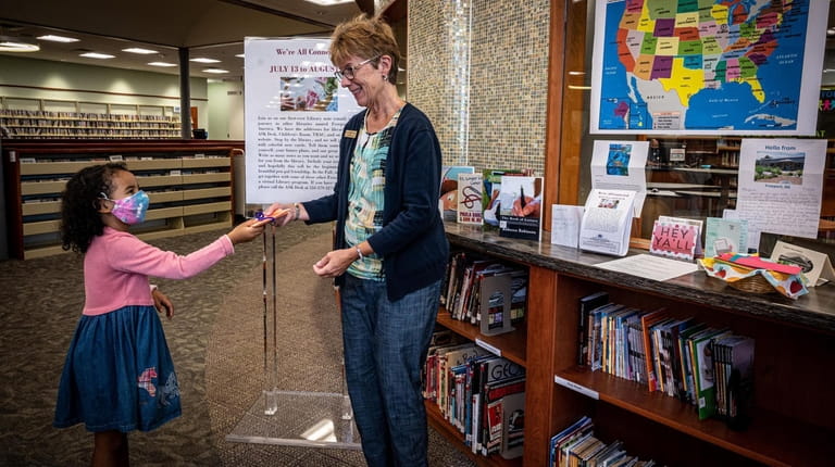 Freeport resident Audrey Smith hands a letter to the programming librarian Maryellen...