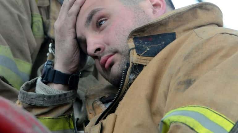 Farmingville firefighter Nick Alfano takes a breather on top of...