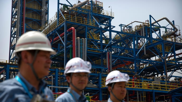 Workers stand near facilities for producing polypropylene at the Sinopec...