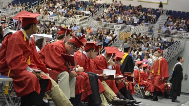 A row of new Syosset High School graduates examine their...