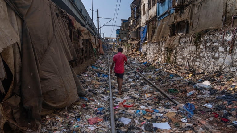 A man walks on a railway track littered with plastic...