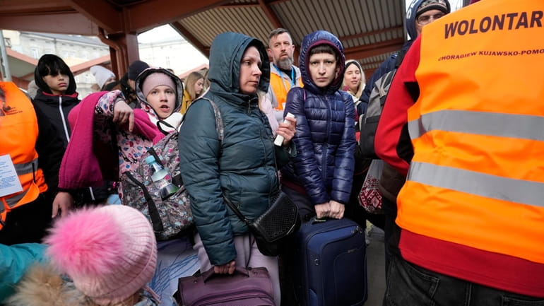 Refugees with children board a train after fleeing the war...