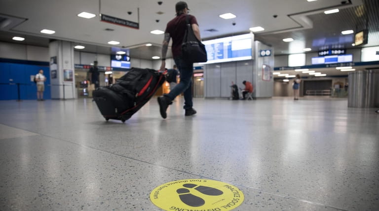 A traveler walks past a social distancing marker at Penn Station...