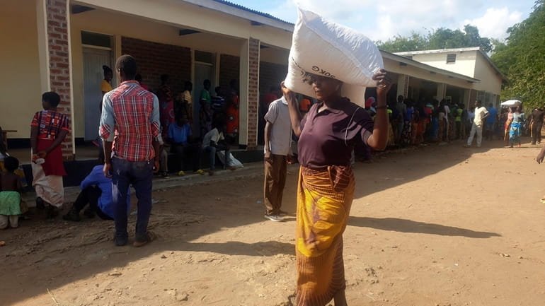 A woman carries a bag of maize meal received at...