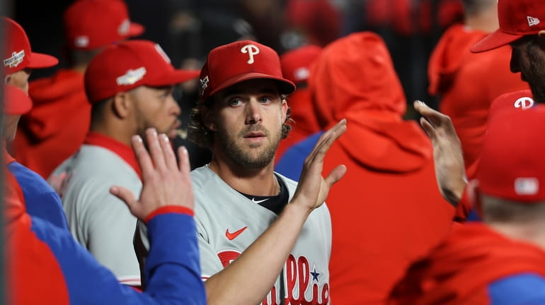 Philadelphia Phillies starting pitcher Aaron Nola is greeted by teammates...