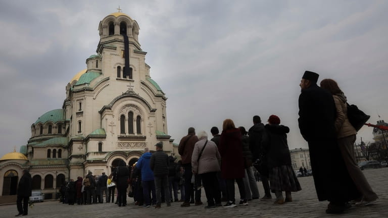 Bulgarian Orthodox believers wait in line to pay their last...