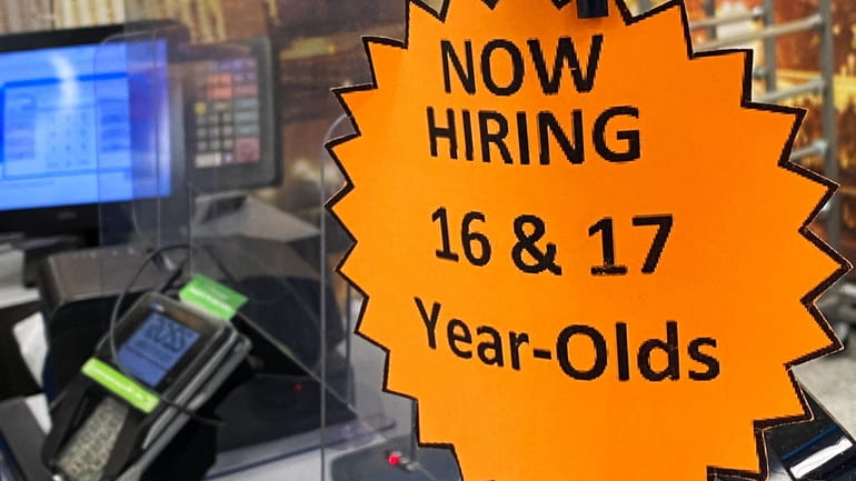 Signage advertising now hiring is displayed on a cash register inside...