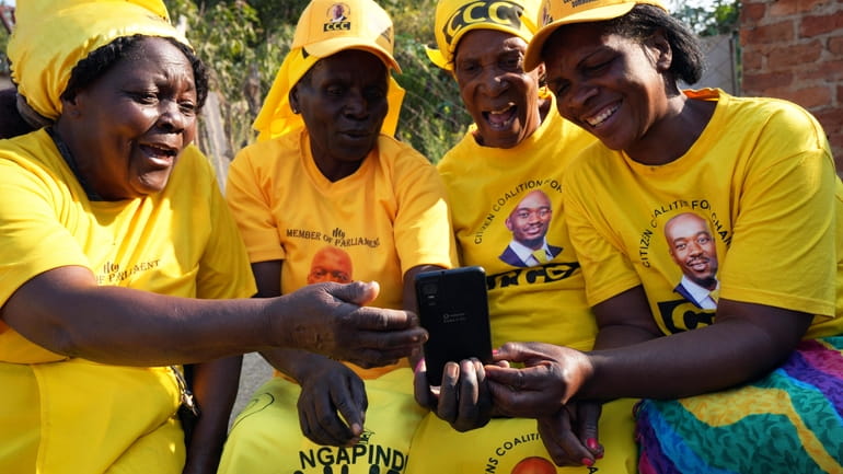 Four women huddle around a cellphone in Zimbabwe's rural Domboshava...