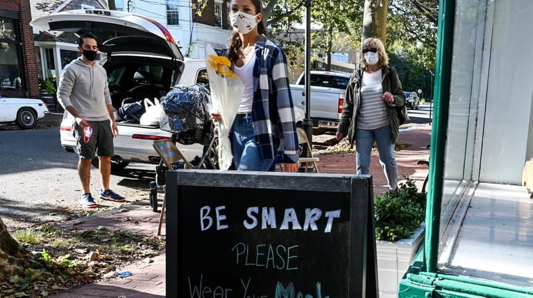 People wearing masks walked past a sign in October promoting...