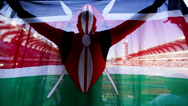 A fan of Kenya holds up a national flag during...