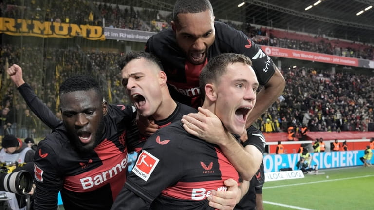Leverkusen's Florian Wirtz, right, celebrates with teammates Jonathan Tah, up,...