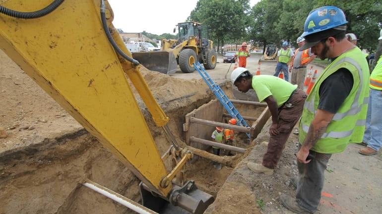Workers dig at the site of the Sewer District 18...