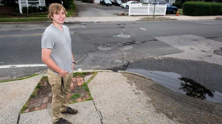 Nick Gluth stands in front of potholes outside his Amityville...