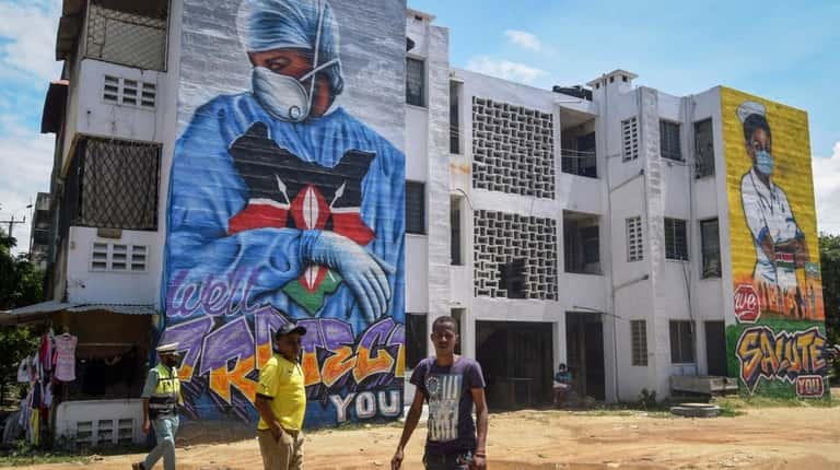 Residents walk Monday by murals that pay tribute to medical workers...