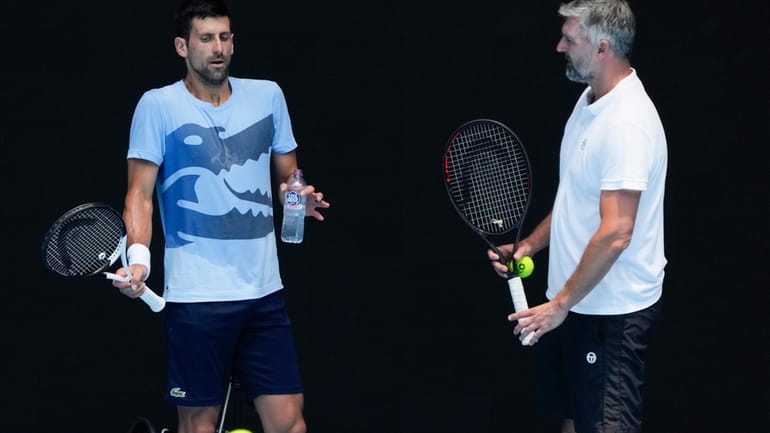 Serbia's Novak Djokovic, left, gestures as talks with coach Goran...