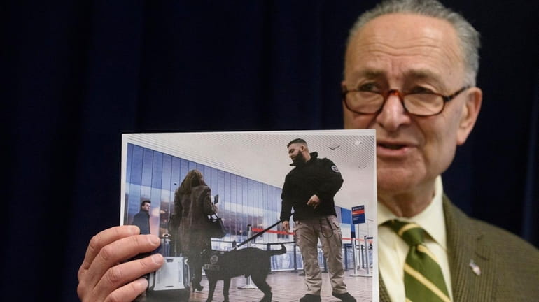 Sen. Chuck Schumer holds a photo of a TSA canine...