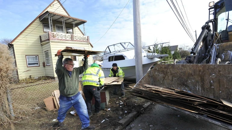 Nick Moligano helps a cleanup crew remove debris from a...
