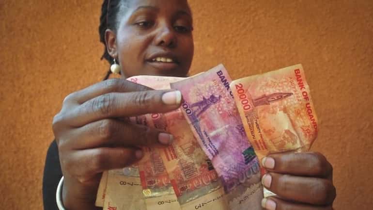 A Ugandan businesswoman who sells cereals counts Ugandan Shilling banknotes...