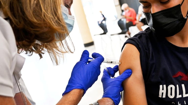 Jayson Molina Majano, 17, of Freeport, is administered a vaccine...