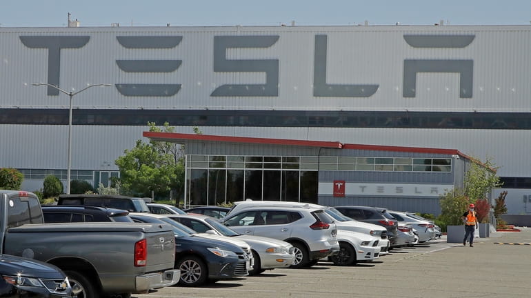 A man walks in the Tesla plant parking lot on...