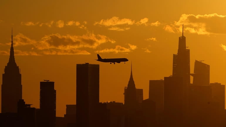 A plane flies with the New York City skyline, Thursday,...