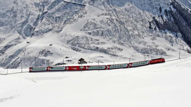 The Glacier express makes its way across a snowy landscape. 