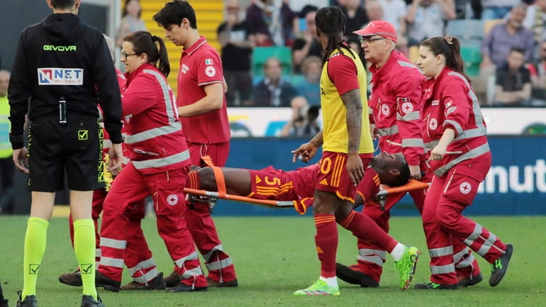 Roma's Evan Ndicka is carried off the pitch on a...