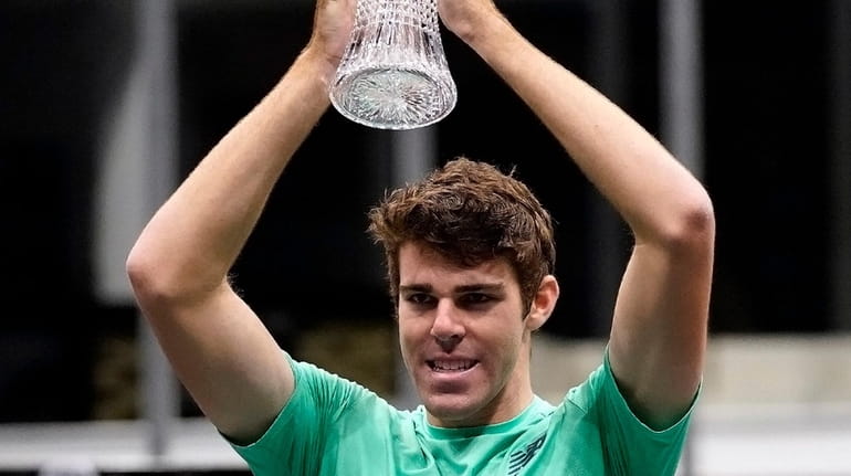 Reilly Opelka hoists the trophy after winning the New York...
