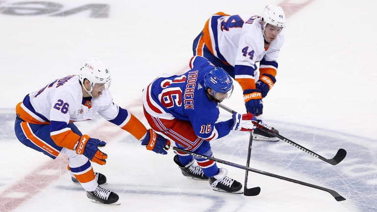 Rangers center Vincent Trocheck skates between Islanders forward Oliver Wahlstrom and center Jean-Gabriel...