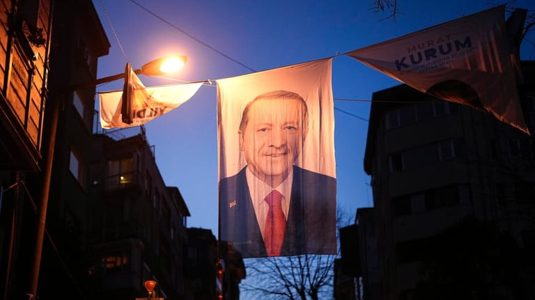 People walk under a campaign banner of Turkish President and...