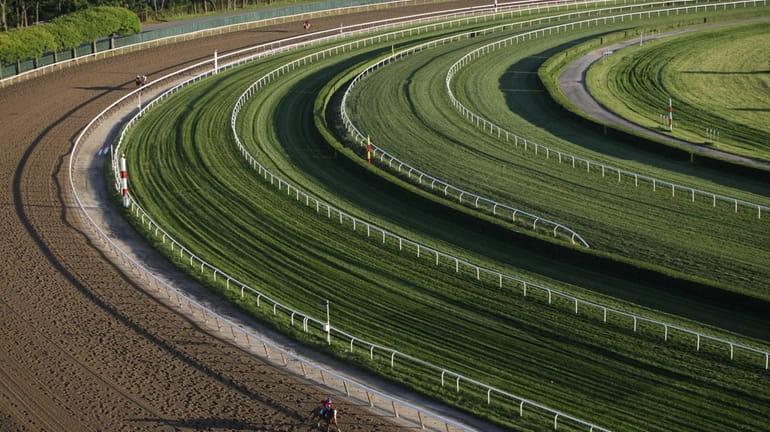 A horse gallops around the fourth turn of the 1...
