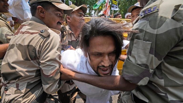 Policemen detain a member of the youth wing of India's...