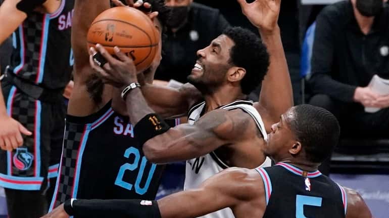 Nets guard Kyrie Irving, center, goes to the basket between...