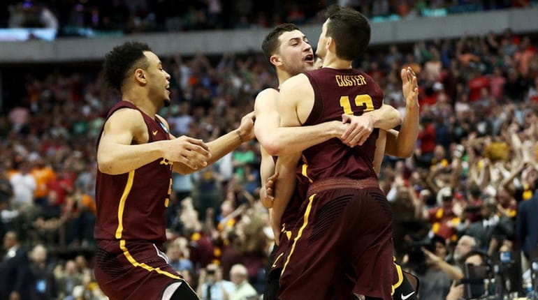 Clayton Custer of the Loyola Ramblers is mobbed by teammates...