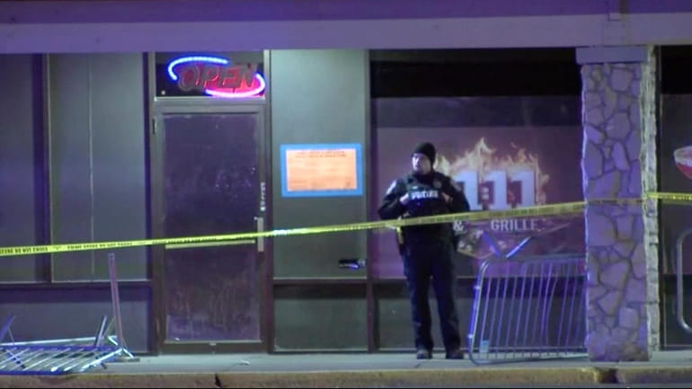 A police officer stands outside a bar after a shooting...