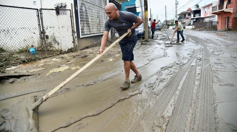People clean the streets in Toa Baja, Puerto Rico, on...