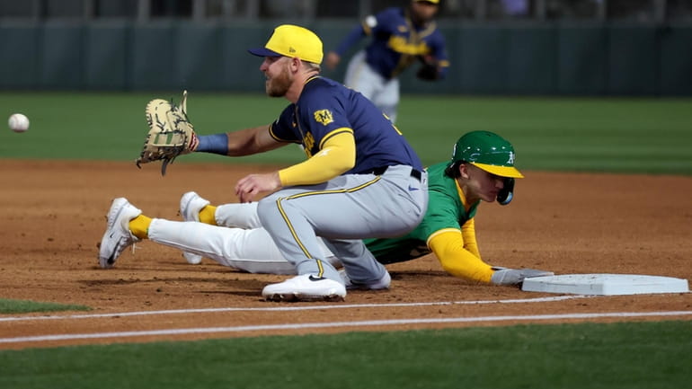 Oakland Athletics' Zack Gelof dives back to first base as...