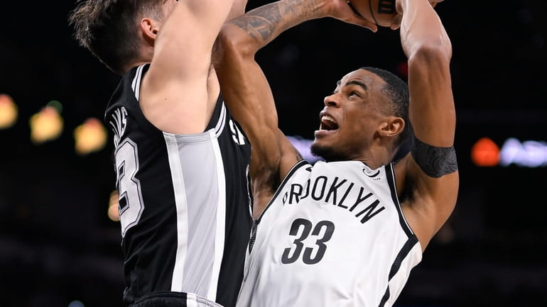 The Nets' Nic Claxton goes to the basket against the Spurs' Zach...