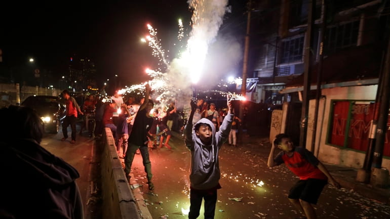 Youths light firecrackers and flares as they celebrate the end...