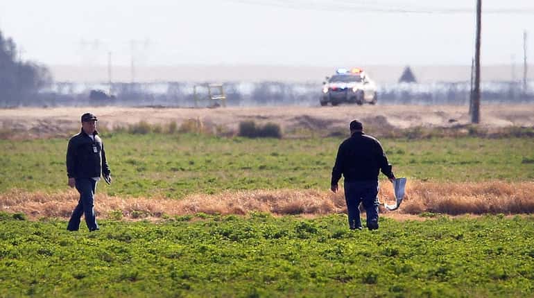 Investigators search a field for debris from an aircraft crash...
