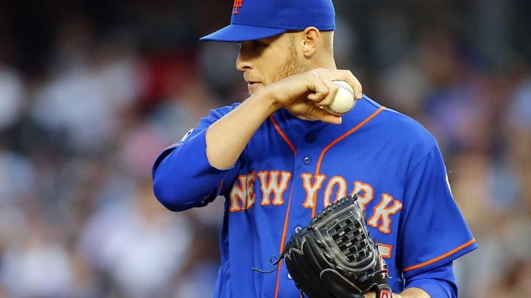 The Mets' Zack Wheeler wipes his face during the first...